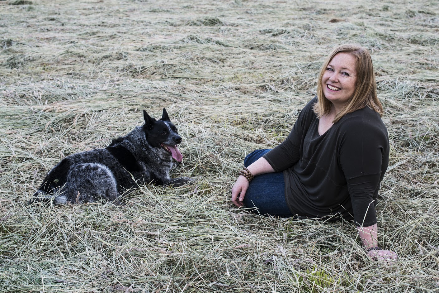 Jasmine Glover sitting relaxing in field with her dog