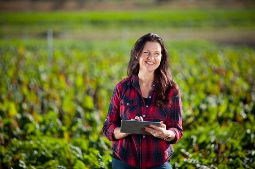 Woman in red checked top standing in field with iPad