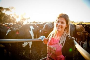 Rural woman in pink apron in front of dairy herd