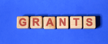 Blue background with wooden blocks that spell out the word grants