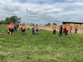 Workshop participants in a Macalister Demonstration Farm paddock listening to presenters talk about flood irrigation operation