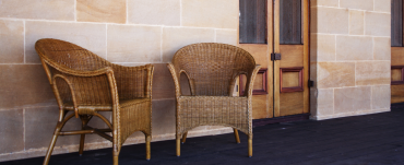 Two wicker chairs on a verandah in front of a door